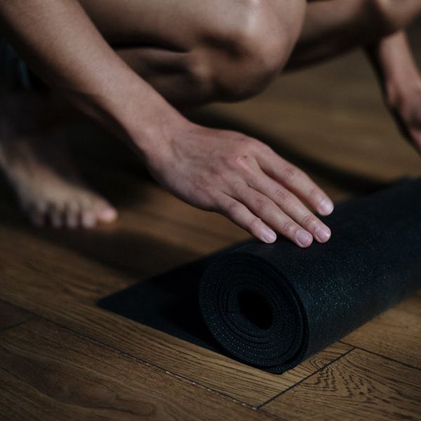 Rolled yoga mat and a wooden floor detail